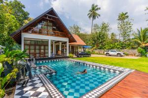 a villa with a swimming pool in front of a house at K Manor in Vāzhākulam