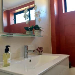 a bathroom sink with a mirror and flowers on it at Apartamento JB - Dona Ana in Lagos +45 photos