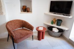 a living room with a chair and a tv at Trullo Màufra in Locorotondo
