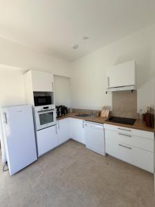 a kitchen with white cabinets and a white refrigerator at Grange 4 couchages in Mios