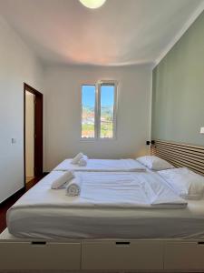 a bedroom with a large white bed with towels on it at Residencial do Vale in Funchal