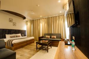 a bedroom with a bed and a couch and a table at Jullundur Hotel & Restaurant in Chandīgarh