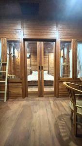 a room with wooden walls and glass doors with a bedroom at Mantra Guesthouse Sidemen in Sidemen