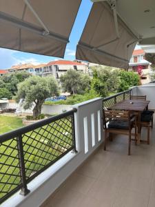 a balcony with a wooden table and chairs and an umbrella at Moiras apartments in Lefkada