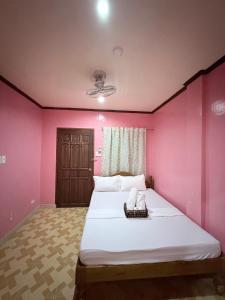 a bedroom with a large bed with pink walls at Tipsy Bay Inn - Malapascua in Daanbantayan +21 photos