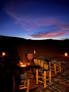 a fire pit with chairs and a table in the desert at Moon Dunes camp in Adrouine
