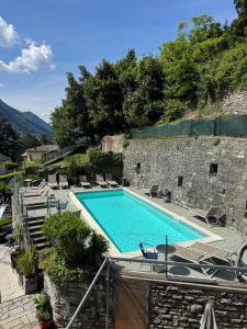 a swimming pool with chairs next to a stone wall at Hotel San Marino in Laglio