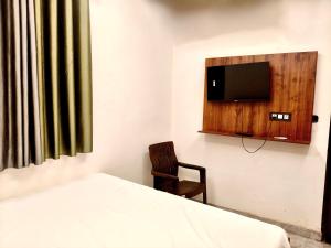 a bedroom with a bed and a chair and a tv at Hotel Sangree in Jewar