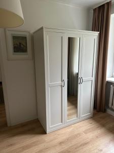 a white cabinet in a room with a mirror at Šaulys in Druskininkai