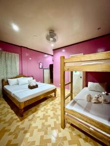 a bedroom with two bunk beds and pink walls at Tipsy Bay Inn - Malapascua in Daanbantayan