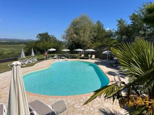 a large swimming pool with chairs and umbrellas at La Pietra Dorata in Rapolano Terme