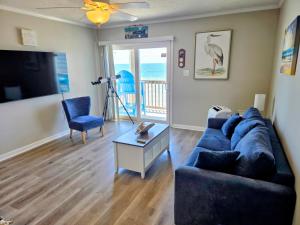 a living room with a blue couch and a table at Beachfront Condo 103 in North Topsail Beach