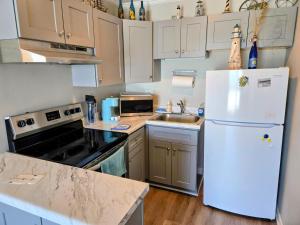 a kitchen with white cabinets and a white refrigerator at Beachfront Condo 103 in North Topsail Beach +21 photos