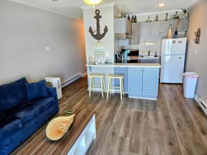 a living room with a blue couch and a kitchen at Beachfront Condo 103 in North Topsail Beach