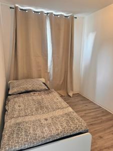 a small bedroom with a bed and a curtain at E&H Appartements in Bregenz