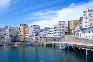 a river with boats in a city with buildings at Costa Canido II in Malpica