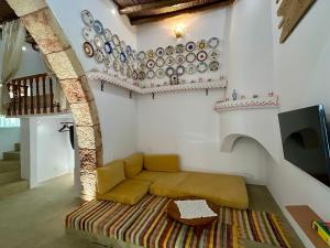 a living room with a couch and plates on the wall at Floura's Kamariko - Authentic Rhodian Village House in Archangelos