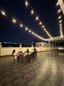 three people sitting at a table on a rooftop at night at Jhigu in Siliguri