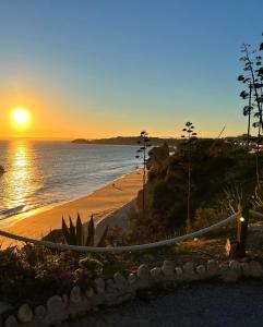 a sunset over a beach with a hammock at Cantinho Lusitano in Portimão
