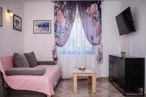 a living room with a pink couch and a window at Apartments Fabijanić in Rab