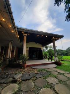 an outdoor pavilion with a stage with tables and chairs at Hansika Guest Inn in Buttala