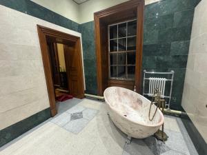 a dirty bath tub in a bathroom with a window at Plas Glynllifon Mansion in Caernarfon