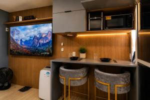 a kitchen with a bar with stools and a tv at PierMauá-Rooftop, Vista, Piscina, Sauna, VLT & Maracanã in Rio de Janeiro