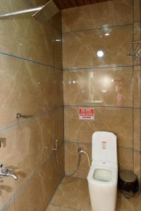 a bathroom with a toilet and a tiled wall at Shridevi Residency in Honāvar