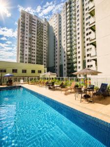 a swimming pool with tables and chairs and buildings at PierMauá-Rooftop, Vista, Piscina, Sauna, VLT & Maracanã in Rio de Janeiro