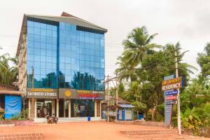 a tall blue glass building with palm trees in the background at Shridevi Residency in Honāvar +19 photos