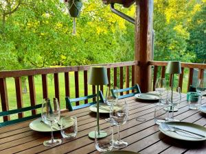 a wooden table with wine glasses on a deck at Pine River Dobrenica in Bihać