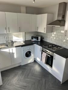 a kitchen with white cabinets and a washing machine at Contractors , holiday house, free parking , sleeps 5 in Knowsley