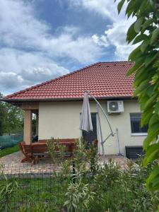 a house with a bench and an umbrella at Murvafürt Vendégház in Cserkeszőlő