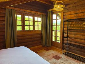 a bedroom with a bed and windows in a log cabin at Pine River Dobrenica in Bihać