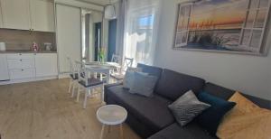 a living room with a couch and a table and a kitchen at Apartament MyMoment in Tupadła