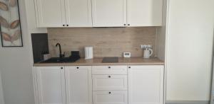 a kitchen with white cabinets and a counter top at Apartament MyMoment in Tupadła