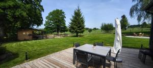 a table and chairs on a wooden deck with a park at En aparté in Vielsalm