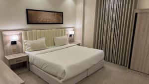 a bedroom with a large bed with white sheets and pillows at سمسمه للشقق المخدومه in Quai