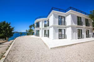 a white house on the shore of a body of water at Hotel Panorama Ksamil in Ksamil
