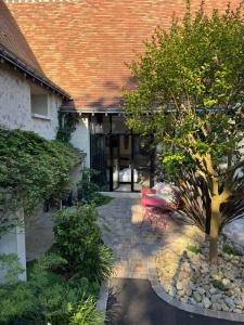 a courtyard of a house with a tree and a building at Guest House de Céline et Benoît in Rivarennes