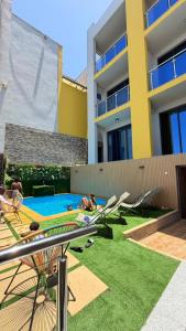 a backyard with a swimming pool with people laying on the grass at Vista Mar Suites in Praia
