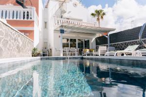 a swimming pool with chairs and a house at Modern 2BR Villa Private Heated Pool, BBQ, Aircon in Costa Adeje by Aqua Vista Tenerife in Callao Salvaje