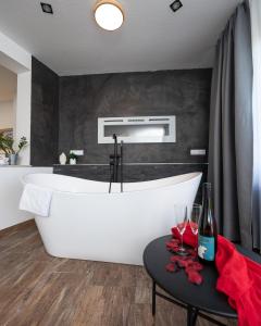 a large white tub in a bathroom with a table at Berghotel Kristall in Idar-Oberstein +40 photos