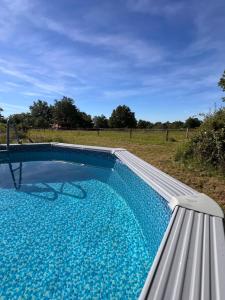 a swimming pool with a bench next to a field at Tiny Gite La Petite Grue in Louroux-Bourbonnais
