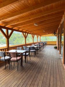 a dining area with tables and chairs on a wooden deck at Riverside Rooms Klos in Klos