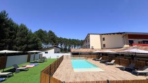 a resort with a pool and chairs and a building at Hôtel Paris Madrid avec Piscine et restauration in Lesperon