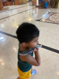 a young child holding a remote control in a room at The Dream City Hotel in Kilinochchi