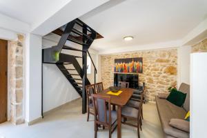 a living room with a dining room table and a spiral staircase at Villa Dora with heated pool & fitness in Gradina