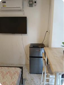 a living room with a table and a television and a desk at Bedroom for 2 in Uptown CDO in Balulang
