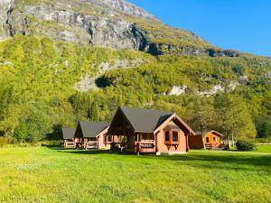a house in a field in front of a mountain at Dalen Gaard camping og hytter in Geiranger